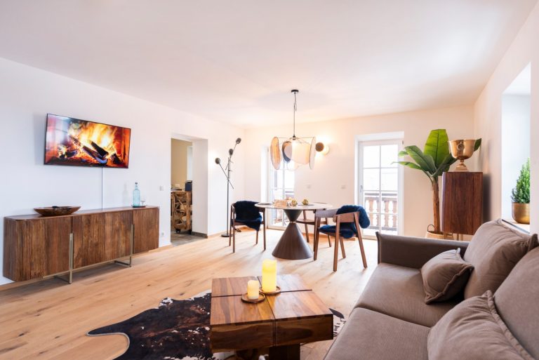 Ein heller, modern und gemütlich eingerichteter Essbereich mit einem runden Holztisch in der Mitte.